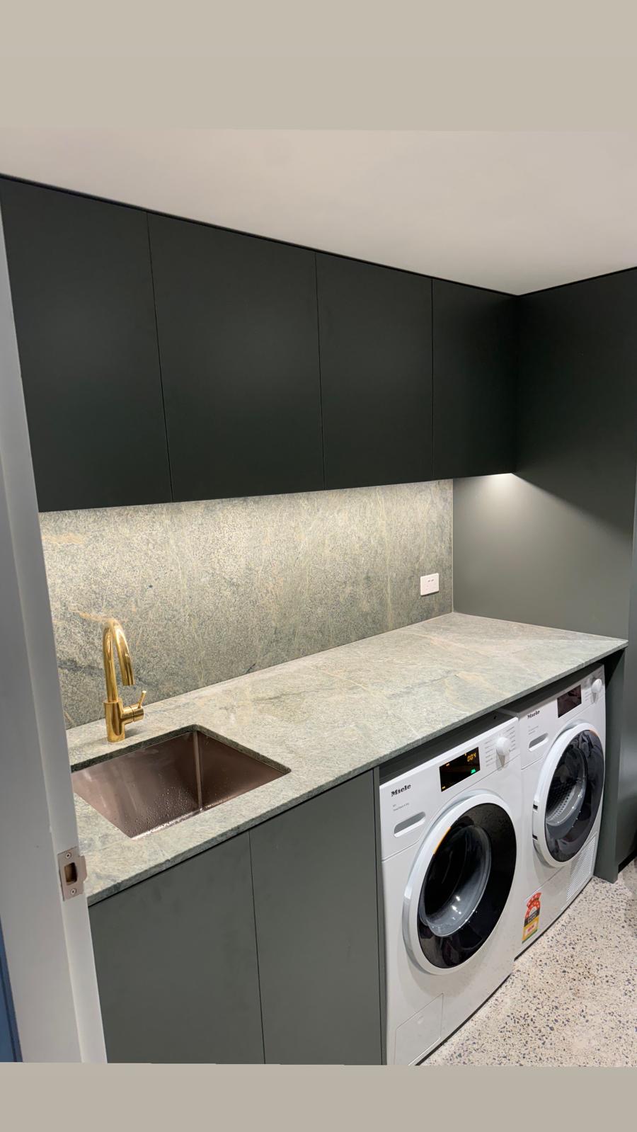 Laundry with stone benchtop and dark joinery