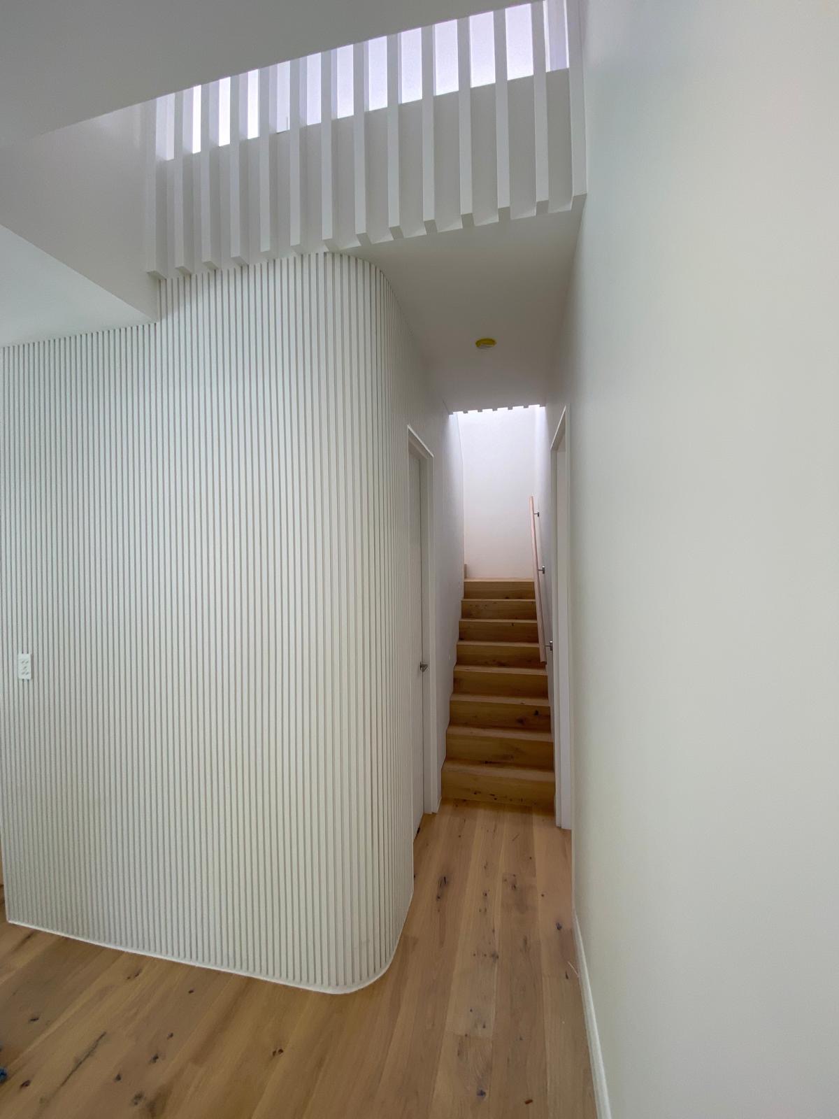 Hallway with curved batten wall and stair beyond