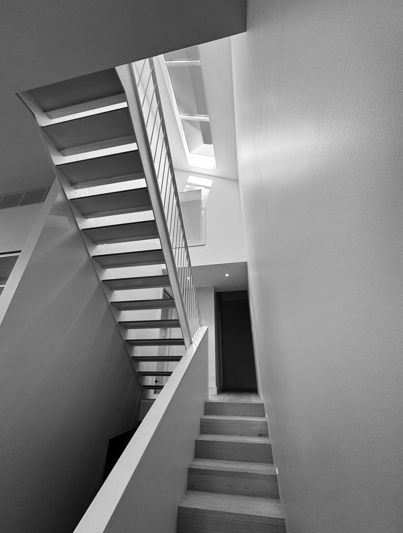 Open-tread white staircase rising toward a skylight